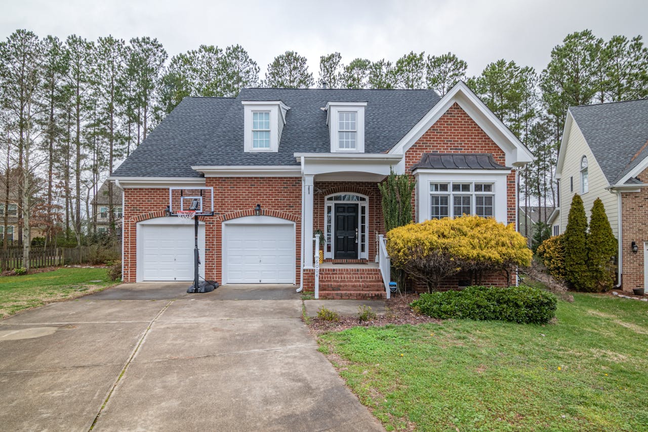Brick suburban home with garage and basketball hoop in a peaceful neighborhood.